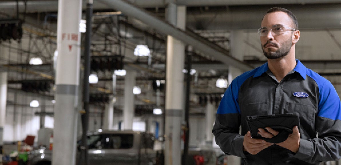 Technicians reviewing information beside a vehicle.