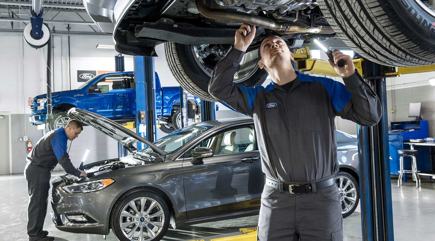 Technician inspecting a vehicle on a lift.