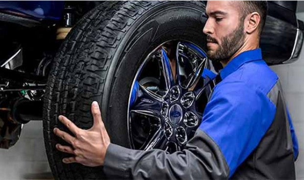 Technician checking a vehicle’s wheel and tire.”