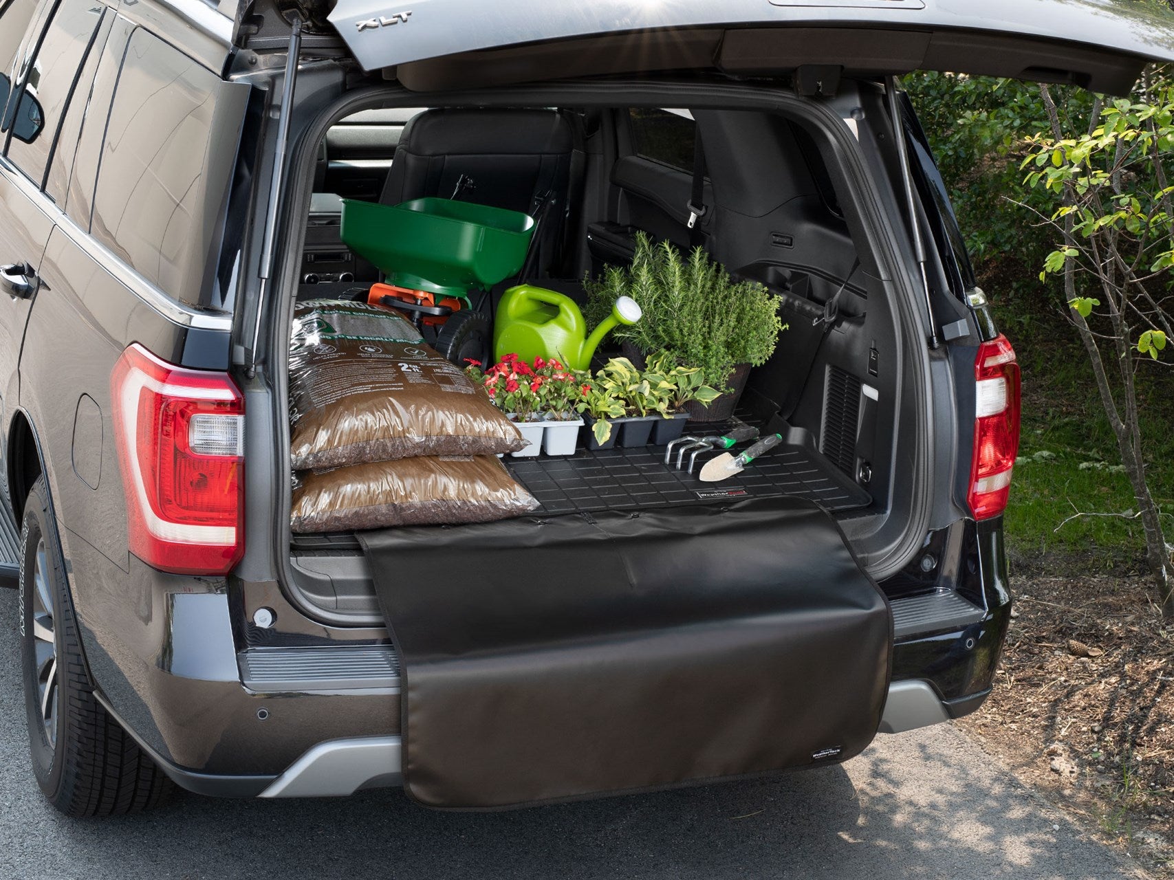 Black trunk liner with gardening supplies on top