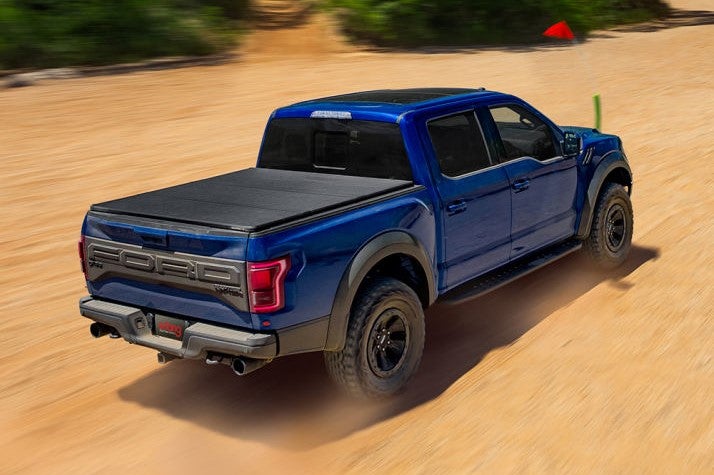 Solid Fold 2.0 hard tri-fold truck bed cover on a blue truck driving on sand