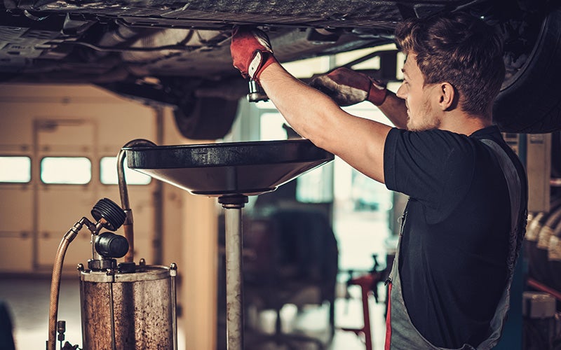 Technician inspecting a vehicle on a lift.